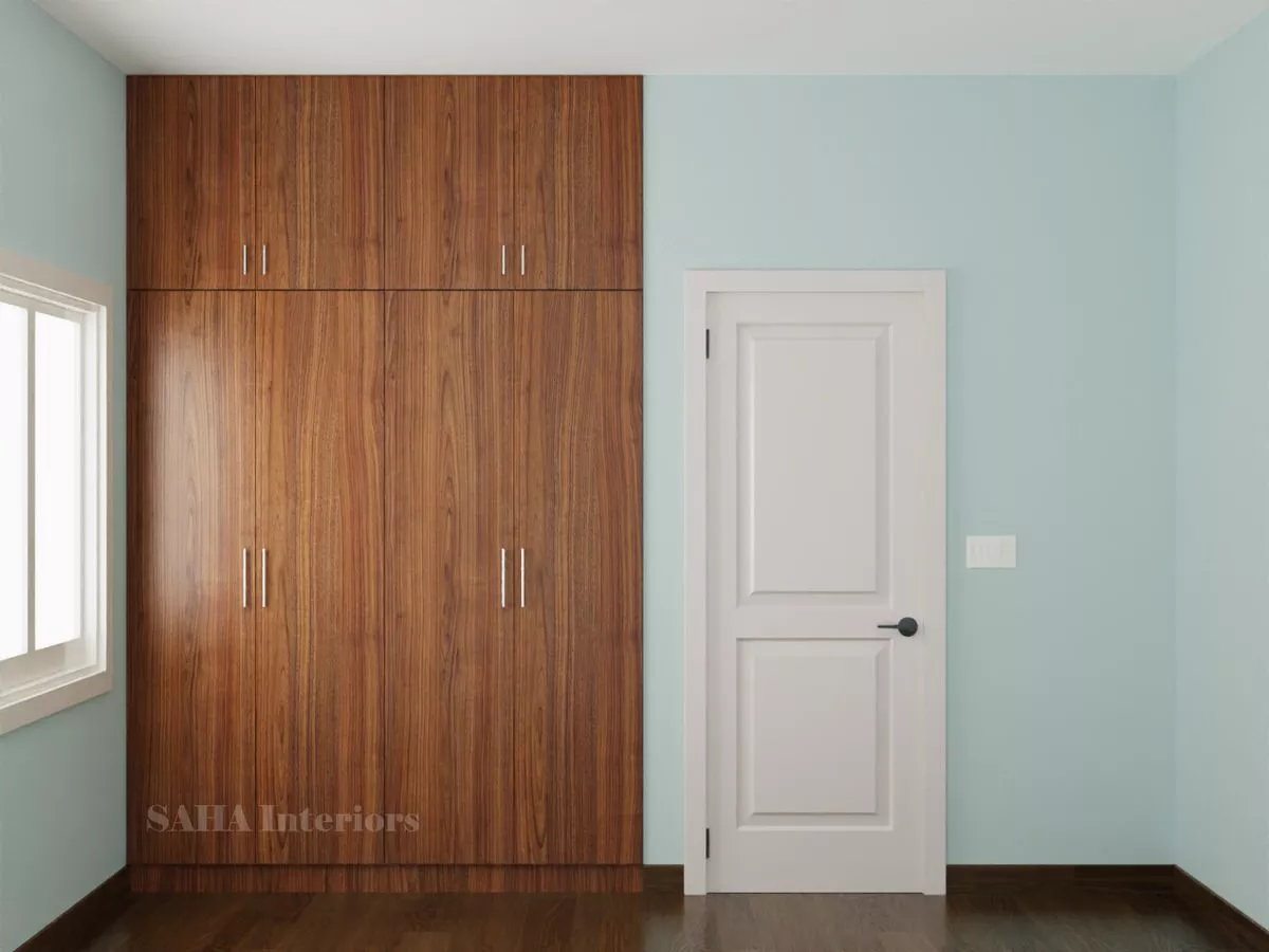 Floor to ceiling 4-door wooden wardrobe with loft storage installed in a Chennai bedroom by SAHA Interiors.