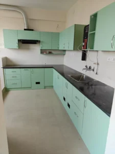 Budget L-shaped modular kitchen with laminate shutters and black granite counter in Chennai