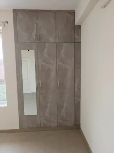 Low budget wardrobe design with mirror shutter and loft in a Chennai flat bedroom
